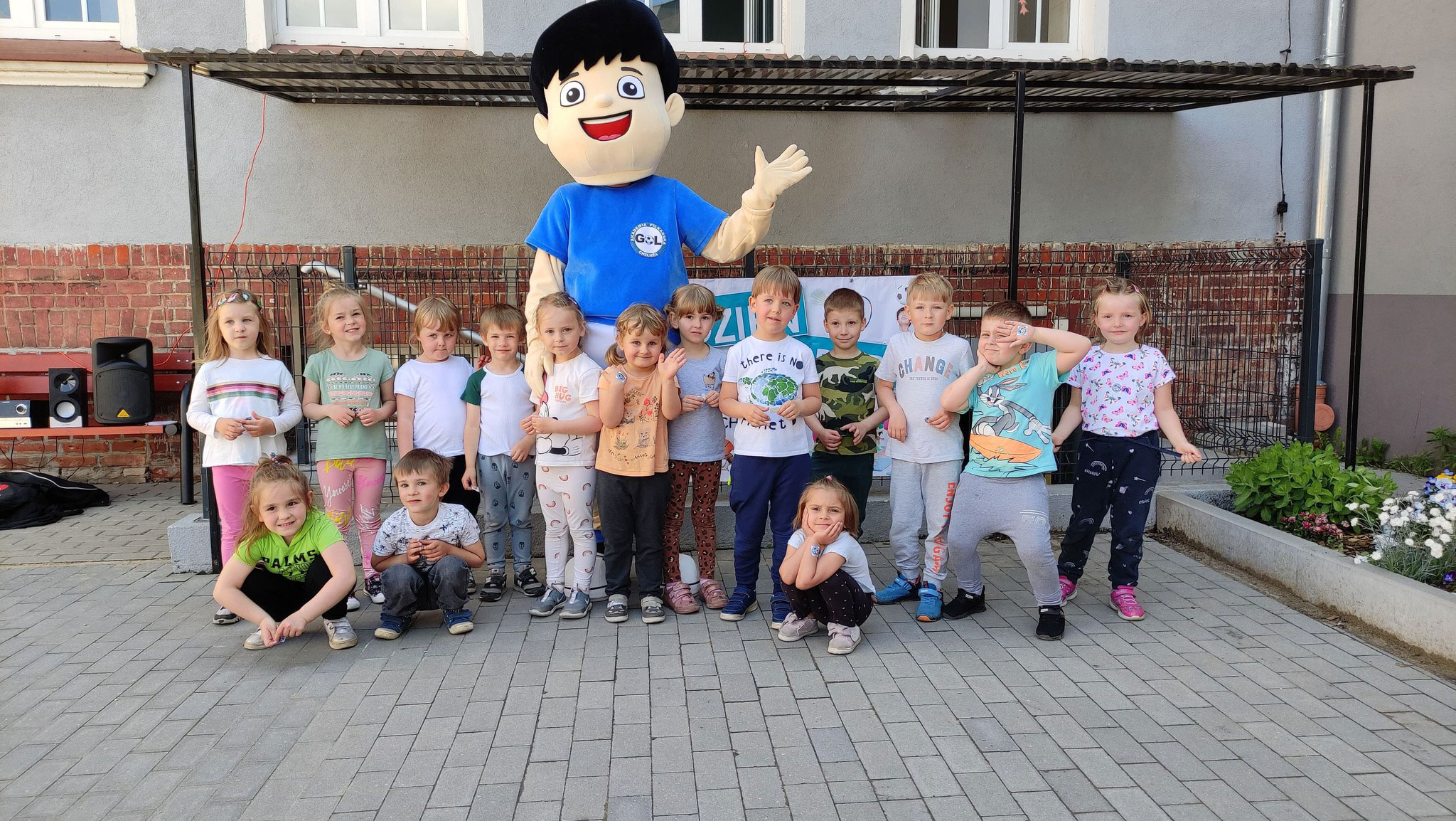 Na fotografii widnieje strój reklamowy chłopiec Golek w towarzystwie grupy uśmiechniętych dzieci